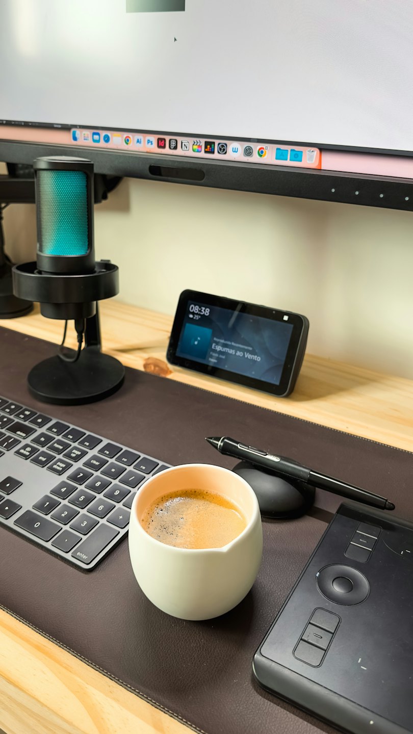 Scrivania moderna con computer, elettronica e tazza di caffè.