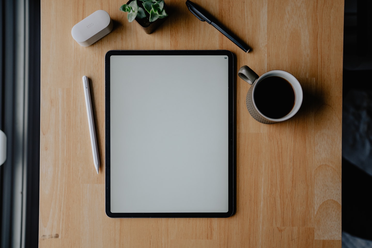 Tablet e cancelleria su una scrivania di legno.